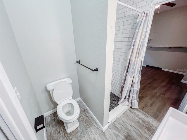 full bathroom with a shower stall, toilet, wood finished floors, and baseboards