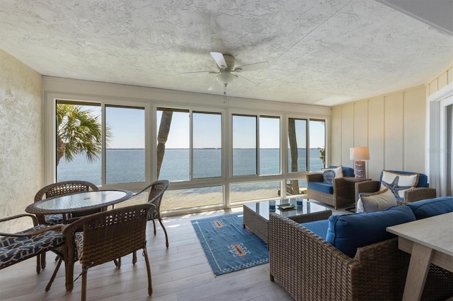 sunroom with a water view, plenty of natural light, and wood finished floors