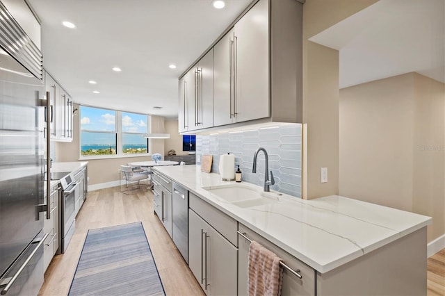 kitchen featuring gray cabinetry, light wood-style floors, a sink, and appliances with stainless steel finishes