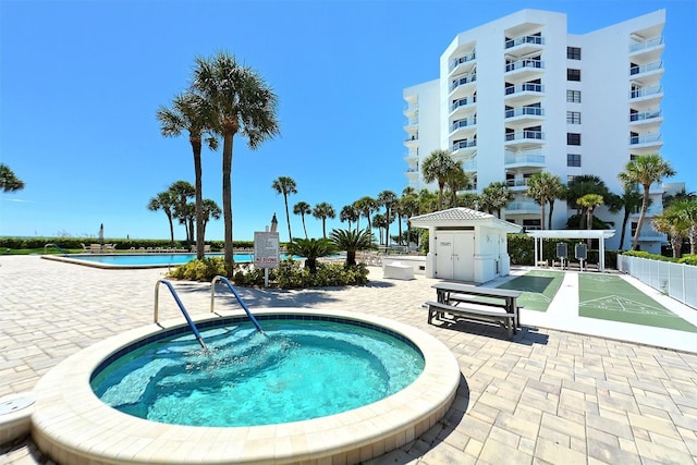 view of swimming pool featuring a water view, shuffleboard, and a hot tub