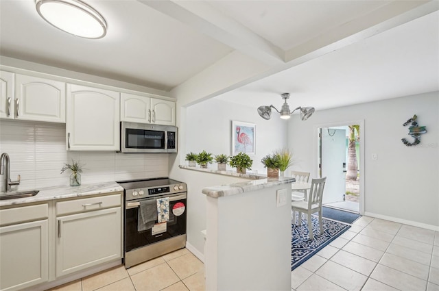 117 7th St N Unit 5, Bradenton Beach, FL 34217 - kitchen with appliances with stainless steel finishes, a sink, tasteful backsplash, light tile patterned flooring, and light stone counters