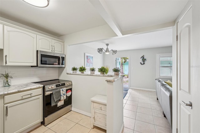 117 7th St N Unit 5, Bradenton Beach, FL 34217 - kitchen with stainless steel appliances, light tile patterned floors, decorative backsplash, a peninsula, and baseboards