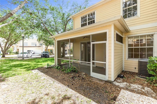 rear view of house featuring a sunroom, a lawn, and central AC