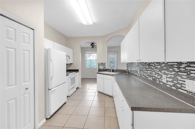 kitchen featuring tasteful backsplash, light tile patterned floors, dark countertops, white appliances, and a ceiling fan