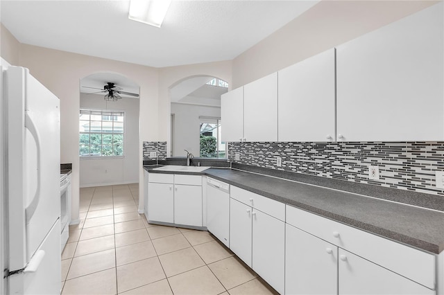 kitchen featuring a sink, dark countertops, white appliances, decorative backsplash, and light tile patterned flooring