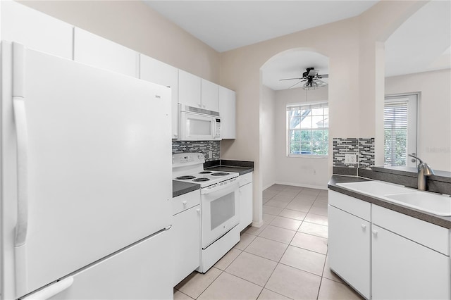 kitchen featuring a sink, a ceiling fan, white appliances, and dark countertops