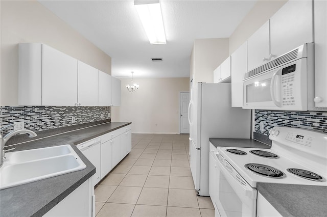 kitchen with visible vents, white cabinets, a sink, dark countertops, and white appliances
