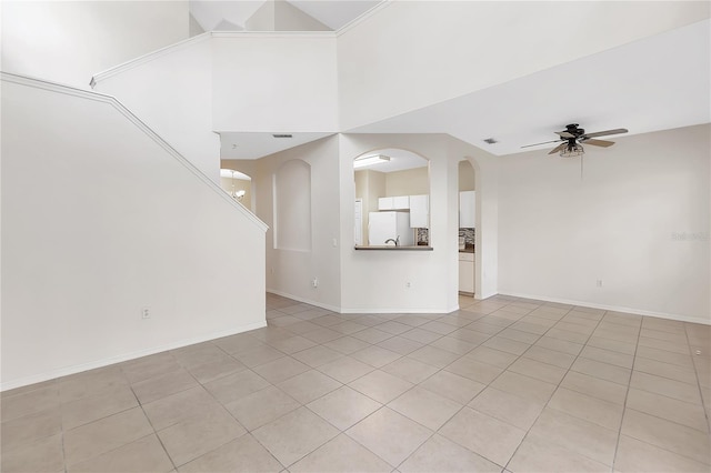 unfurnished living room featuring visible vents, baseboards, arched walkways, a ceiling fan, and a towering ceiling