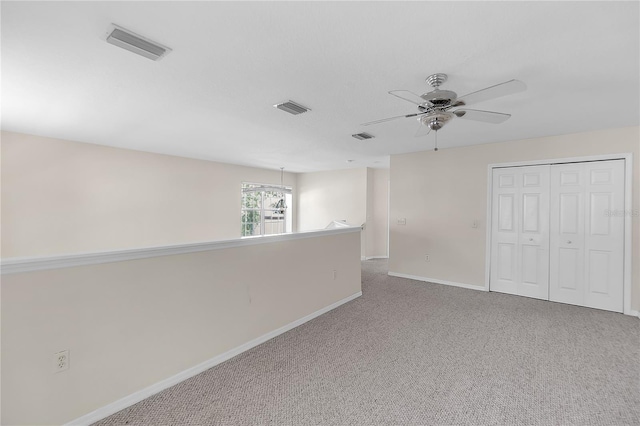 carpeted spare room featuring visible vents, baseboards, and a ceiling fan