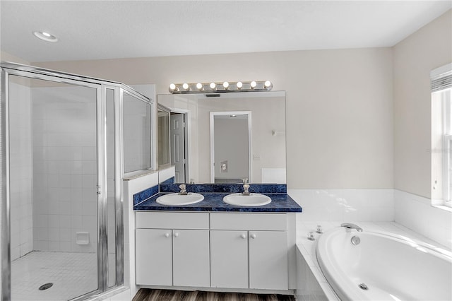 bathroom featuring a shower stall, a garden tub, and a sink