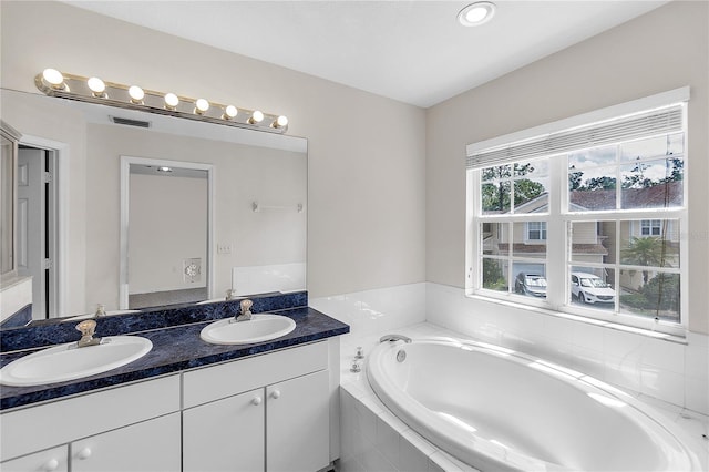 full bath with a sink, double vanity, and a garden tub