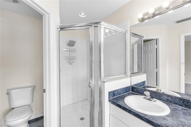 bathroom featuring a shower stall, vanity, visible vents, and toilet