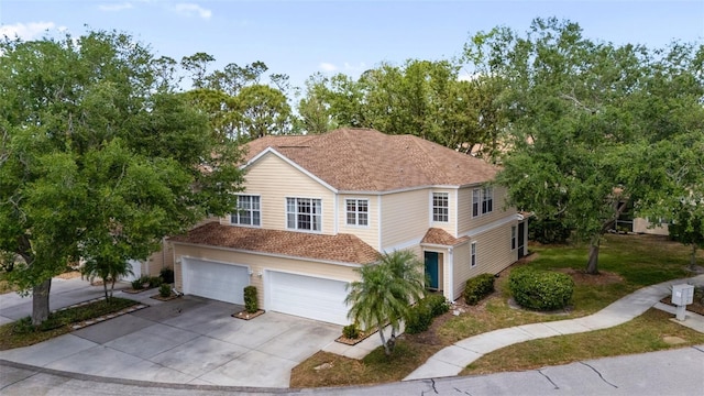 traditional-style house featuring a shingled roof, driveway, and an attached garage