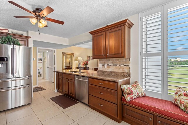 kitchen with light tile patterned flooring, stainless steel appliances, a ceiling fan, tasteful backsplash, and a sink