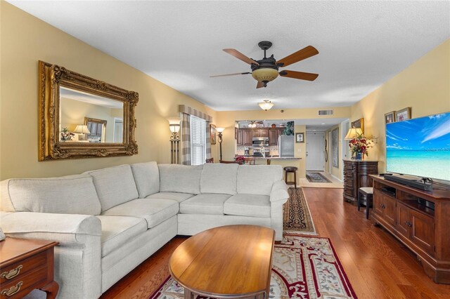 living area featuring a ceiling fan, dark wood-style flooring, and visible vents