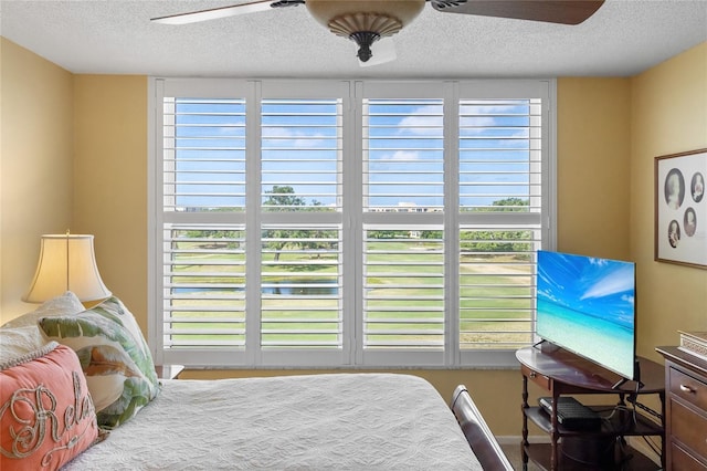 bedroom featuring multiple windows, ceiling fan, and a textured ceiling