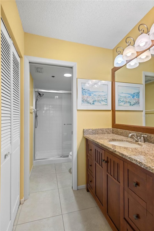 bathroom with a closet, a textured ceiling, visible vents, a shower stall, and vanity