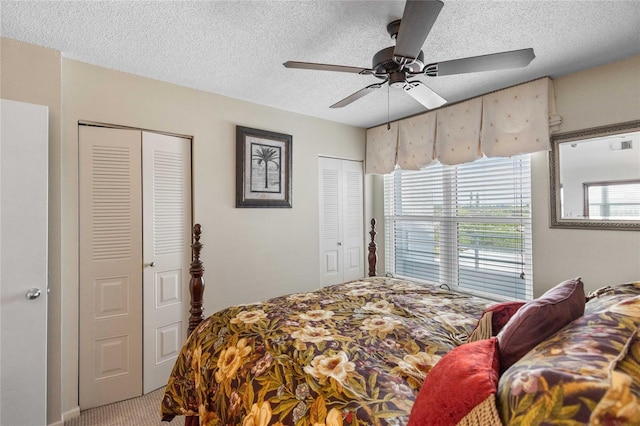 bedroom featuring a textured ceiling, carpet, a ceiling fan, and two closets