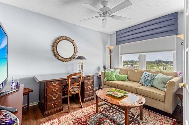 living room featuring a textured ceiling, baseboards, ceiling fan, and wood finished floors