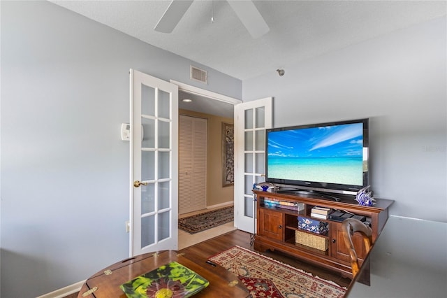 living area with a textured ceiling, visible vents, wood finished floors, a ceiling fan, and french doors