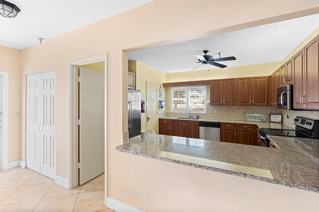 kitchen featuring light stone countertops, a sink, light tile patterned floors, and appliances with stainless steel finishes