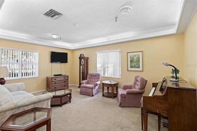 living room featuring baseboards, a textured ceiling, visible vents, and light colored carpet