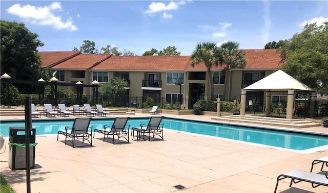 community pool featuring fence, a gazebo, and a patio area