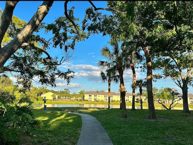 view of home's community with a water view and a lawn
