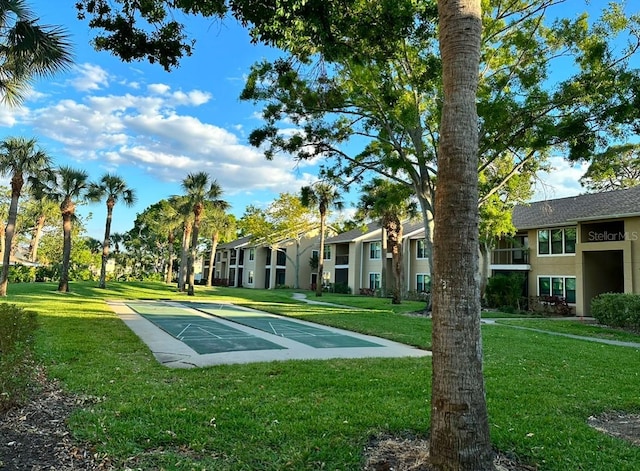 view of property's community featuring shuffleboard, a lawn, and a residential view