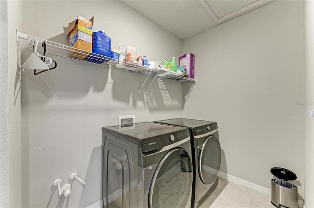 laundry room with light tile patterned flooring, baseboards, washer and dryer, and laundry area