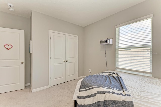 bedroom with light carpet, baseboards, and a closet