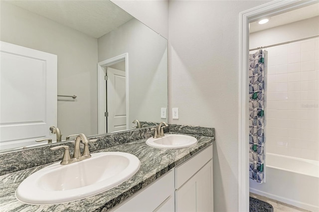 bathroom featuring double vanity, shower / bathtub combination with curtain, and a sink
