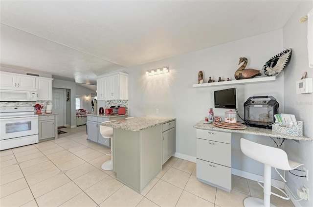 3053 Monica Pkwy, Sarasota, FL 34234 - kitchen featuring backsplash, a peninsula, white appliances, and light tile patterned floors