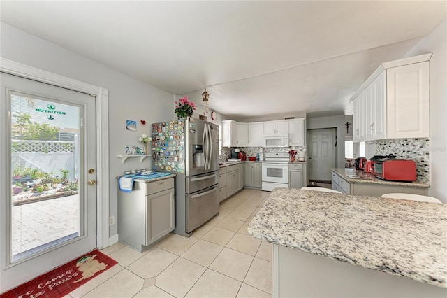 3053 Monica Pkwy, Sarasota, FL 34234 - kitchen featuring light tile patterned flooring, white appliances, gray cabinets, backsplash, and white cabinetry