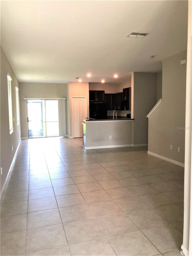 unfurnished living room featuring baseboards, visible vents, and light tile patterned floors