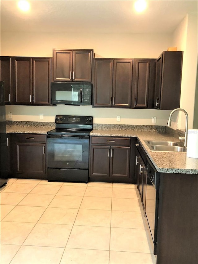 kitchen featuring black appliances, dark brown cabinetry, a sink, and light tile patterned floors