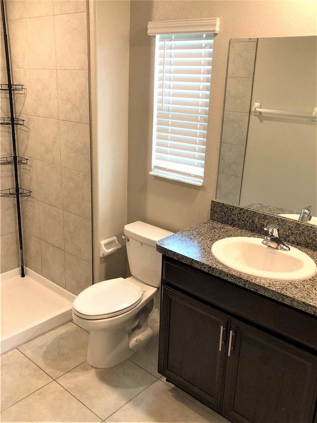 full bath with toilet, vanity, tile patterned floors, and a tile shower