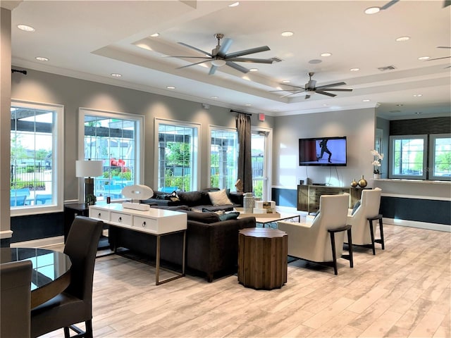 living room with visible vents, crown molding, a ceiling fan, light wood-type flooring, and a tray ceiling