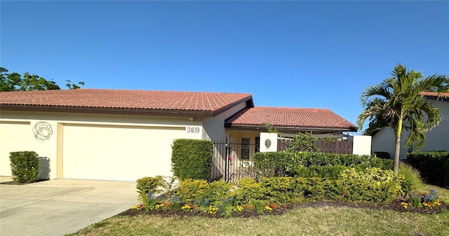 3409 Montilla Ct Unit 8410, Sarasota, FL 34232 - view of front of property featuring a garage, fence, stucco siding, a tiled roof, and driveway