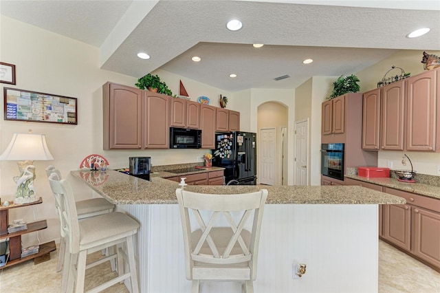 8136 Snowy Egret Pl, Bradenton, FL 34202 - kitchen with black appliances, a breakfast bar, a peninsula, recessed lighting, and light stone countertops