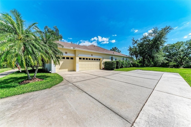 8136 Snowy Egret Pl, Bradenton, FL 34202 - view of side of home featuring an attached garage, concrete driveway, stucco siding, and a lawn