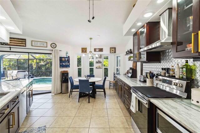 18033 Edgewater Dr, Port Charlotte, FL 33948 - kitchen featuring backsplash, hanging light fixtures, light tile patterned floors, wall chimney range hood, and stainless steel appliances