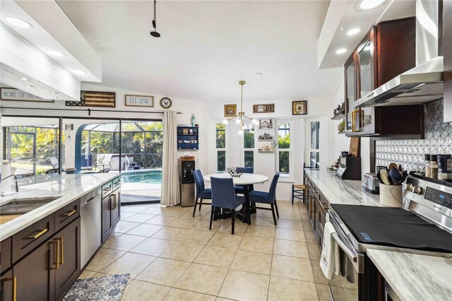 18033 Edgewater Dr, Port Charlotte, FL 33948 - kitchen featuring wall chimney range hood, tasteful backsplash, light tile patterned floors, and stainless steel appliances