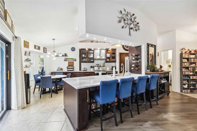 18033 Edgewater Dr, Port Charlotte, FL 33948 - kitchen with wall chimney range hood, glass insert cabinets, vaulted ceiling, and stainless steel range with electric stovetop