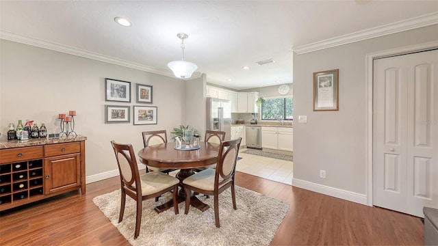 dining space with light wood-style flooring, baseboards, ornamental molding, and recessed lighting