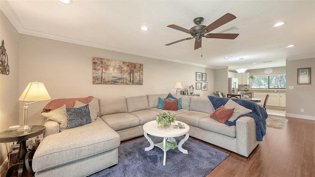 living area with ornamental molding, a ceiling fan, visible vents, recessed lighting, and wood finished floors