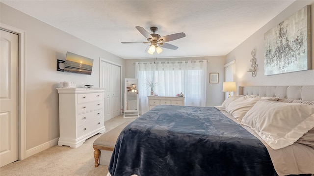 bedroom with a closet, light colored carpet, baseboards, and a ceiling fan
