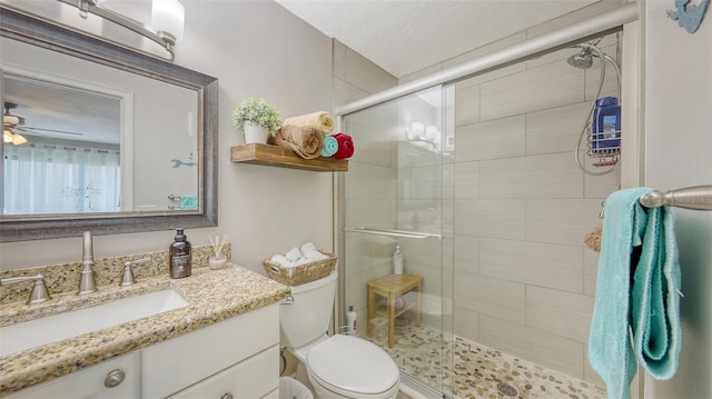 bathroom with toilet, a stall shower, vanity, and ceiling fan
