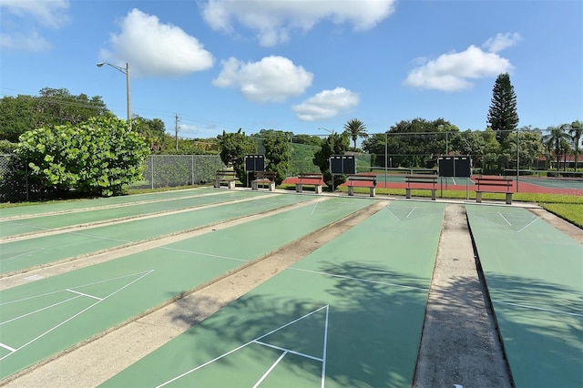 surrounding community featuring shuffleboard, a tennis court, and fence