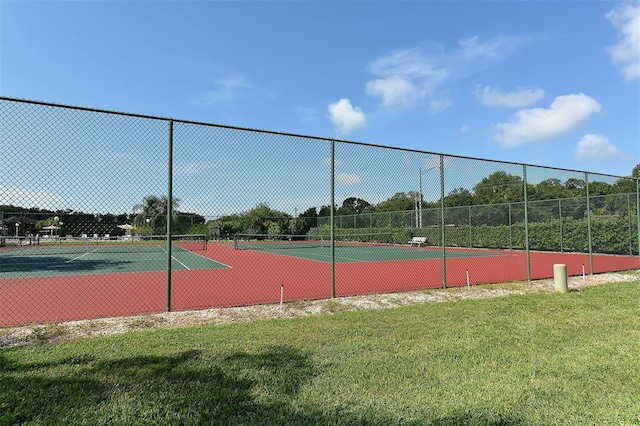 view of tennis court with fence and a lawn